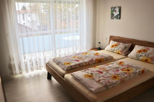 two beds in a room with a large window at Ferienwohnungen Böhme in Konstanz