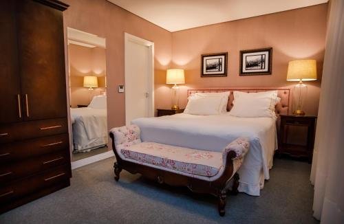 a bedroom with a large bed with a bench in it at Sofistic Hotel in Itapema