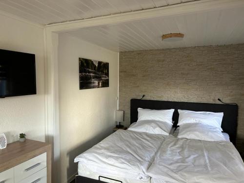 a bedroom with a bed with white sheets at Bungalow Schwarzatalblick in Bad Blankenburg Ortsteil Böhlscheiben in Bad Blankenburg