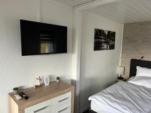 a bedroom with a bed and a television on the wall at Bungalow Schwarzatalblick in Bad Blankenburg Ortsteil Böhlscheiben in Bad Blankenburg