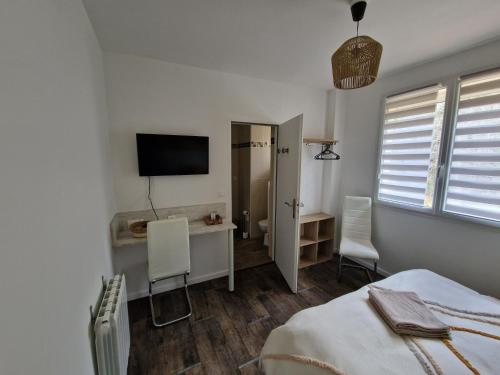 a bedroom with a bed and a desk and a television at Le Nid Cabailla in Coimères