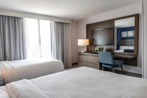 a hotel room with two beds and a mirror at Embassy Suites by Hilton Tulsa I-44 in Tulsa