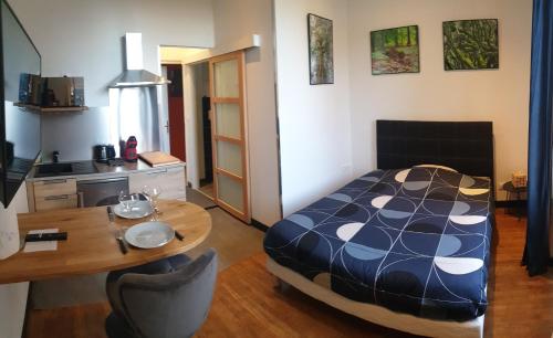 a bedroom with a bed and a table and a kitchen at Le studio du Parc au cœur de Chaumont in Chaumont