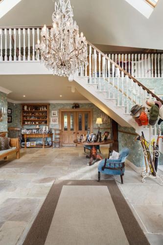 a large living room with a staircase and a chandelier at Cherrygarth Cottage in White Hall
