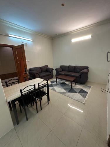 a living room with a couch and a table and chairs at الديوان النجدي للشقق المخدومة اقتصادي in Ukaz