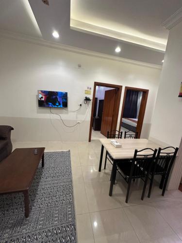 a living room with a table and chairs and a tv at الديوان النجدي للشقق المخدومة اقتصادي in Ukaz