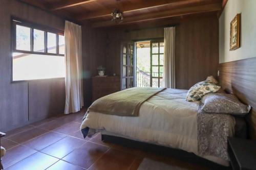 1 dormitorio con 1 cama en una habitación con ventana en WolfsHaus: Sossego junto a natureza a 30km de Ctba, en Campina Grande do Sul