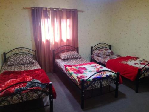 two twin beds in a room with a window at Dana INN in At-Tafilah