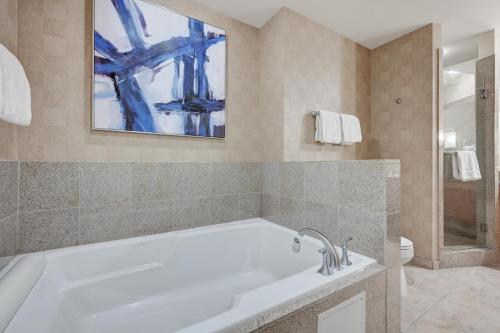 a bathroom with a tub and a painting on the wall at Spacious Retro 1 BR Condo with Sphere Views 1 Block from Vegas Strip NO Resort Fees in Las Vegas