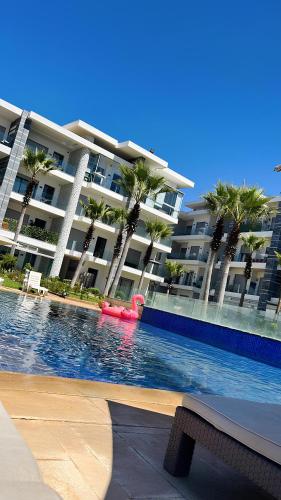 a swimming pool in front of a large building with palm trees at Appartement de luxe en bord de mer avec piscine in Mansouria