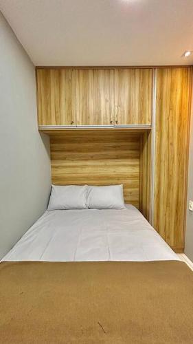 a bedroom with a large white bed with a wooden headboard at Flat Villa Monte Castelo in Bezerros