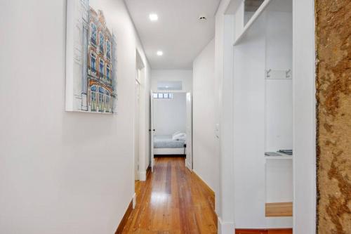 a hallway with white walls and wood floors at São Roque Sweet Burgo in Aveiro