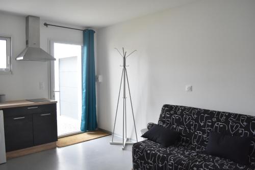- un salon avec un canapé noir et un tripode dans l'établissement Studio privatif tout équipé dans résidence de l'hôte, à Sainte-Flaive-des-Loups