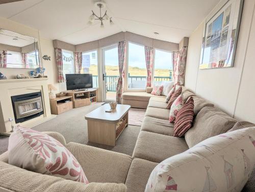 a living room with a couch and a tv at Peacehaven, Ynyslas, Borth in Borth