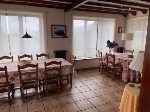 a dining room with a table and chairs and windows at Prau del Urogallo in Ribadesella