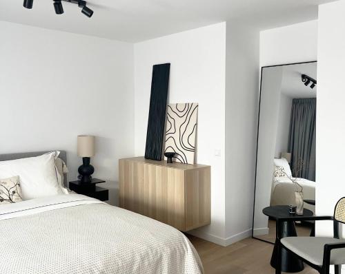 a white bedroom with a bed and a chair at Anflor studio in Zwijndrecht