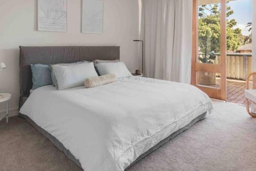 a large white bed in a bedroom with a balcony at The Ace - Byron Bay in Byron Bay