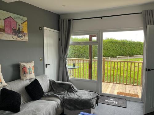 a living room with a couch and a sliding glass door at S and S Chalets - 2 - Mablethorpe in Mablethorpe