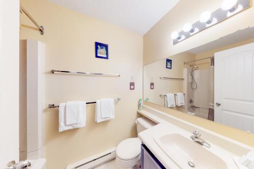 a bathroom with a sink and a toilet and a mirror at Snow Ghost Inn 326 in Big White