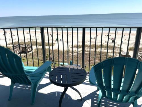three chairs and a table on a balcony overlooking the beach at Blue Palmetto Vacation Rentals in Myrtle Beach