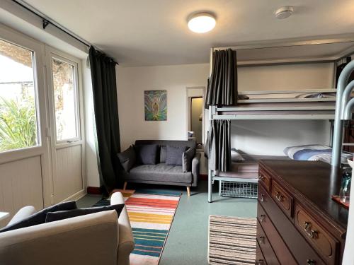 a bedroom with bunk beds and a couch and a chair at Lands End Hostel and B&B in Sennen