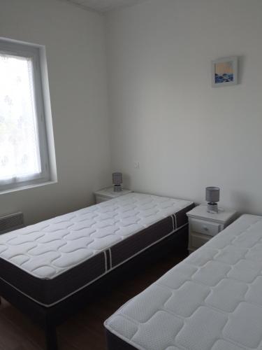 deux lits jumeaux dans une chambre avec fenêtre dans l'établissement maison rénovée en 2022, à Barbâtre