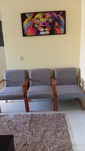 a waiting room with two chairs and a painting on the wall at Apartamento por temporadas in Rio Verde