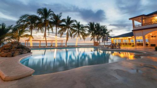 a large swimming pool in front of a building with palm trees at Hotel Bahía Paraíso in San Blas