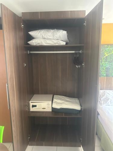 a brown cabinet with two pillows and a bed at Flat suite morador Hotel in Nova Iguaçu