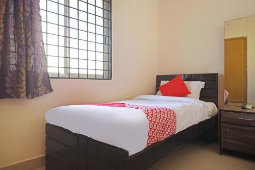 a bedroom with a bed with a red pillow at OYO Athithi Comforts in Bangalore