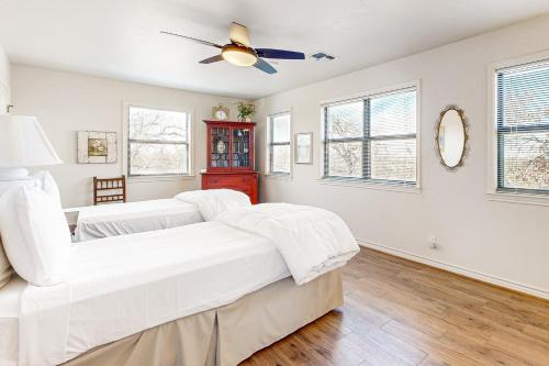 a white bedroom with two beds and a ceiling fan at Casa Austin in Fredericksburg
