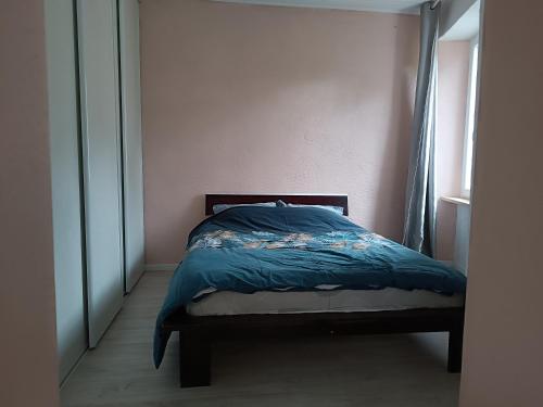 a bed with a blue comforter in a bedroom at Maison meublé au centre de Luc in Luc-en-Diois