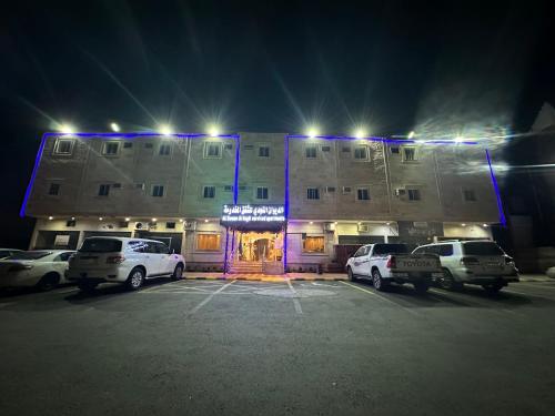 um edifício com carros estacionados num parque de estacionamento à noite em الديوان النجدي للشقق المخدومة em Ukaz