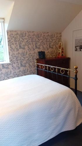 1 dormitorio con 1 cama con colcha blanca en Gardeners Cottage, en Kilcock