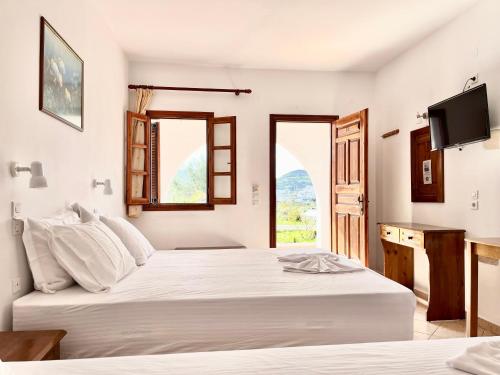 a bedroom with two beds and a tv and a window at Nicolas Studios in Skala