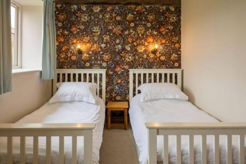 2 weiße Betten in einem Zimmer mit einer Wand in der Unterkunft Wood Cottage in York