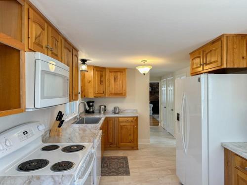 a kitchen with wooden cabinets and a white refrigerator at 2 Miles to Nauset & Coast Guard Beach Dog Friendly in Eastham