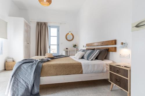 a white bedroom with a large bed and a mirror at Studios Kontos in Mikri Vigla