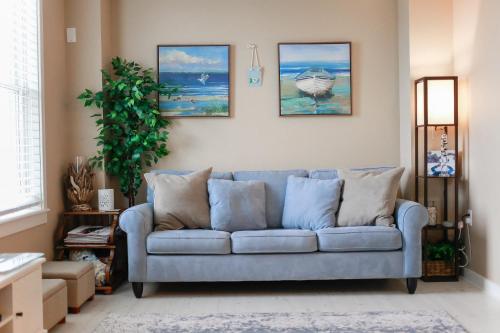 a living room with a blue couch and paintings on the wall at Sojourn Relaxing Condo near the Beach with Pool in Virginia Beach