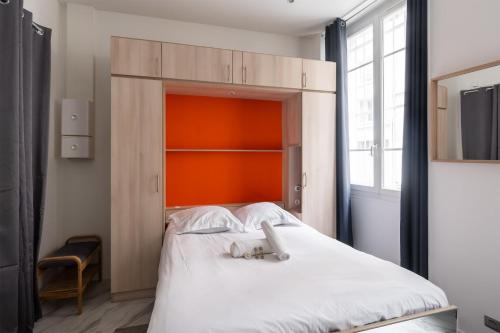 - une chambre avec un grand lit blanc et une tête de lit orange dans l'établissement Studio Exelmans - Welkeys, à Paris