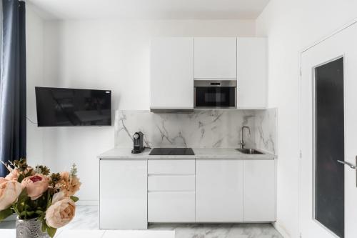 une cuisine blanche avec un évier et un micro-ondes dans l'établissement Studio Exelmans - Welkeys, à Paris