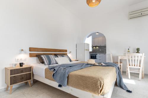 a white bedroom with a large bed and a kitchen at Studios Kontos in Mikri Vigla