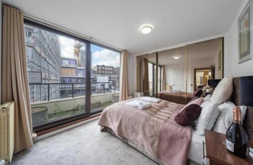 ein Schlafzimmer mit einem Bett und einem großen Fenster in der Unterkunft Luxurious Apartments in Mayfair in London