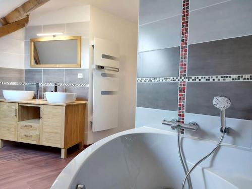 a bathroom with a white tub and two sinks at Gîte de la Petite Noërie - 11 personnes in Saint-Georges-le-Fléchard