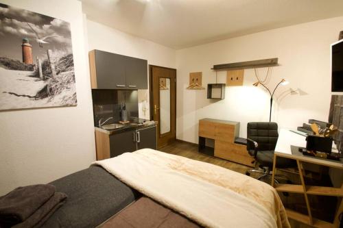 a bedroom with a bed and a desk and a kitchen at Serviced Business Apartment in Lorsch