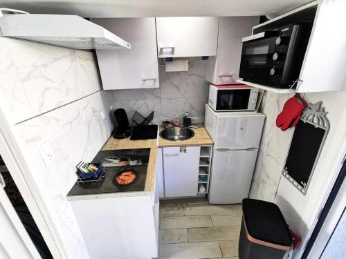 Elle comprend une petite cuisine avec des placards blancs et un réfrigérateur blanc. dans l'établissement Résidence Etoile Du Sud - 2 Pièces pour 4 Personnes 401, à Leucate