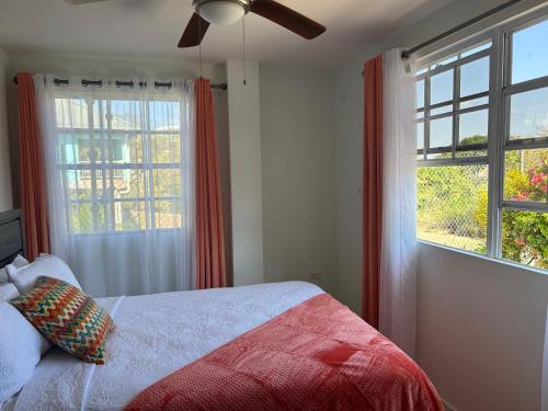 a bedroom with a bed and two windows at Faith's Villa Tobago in Diamond