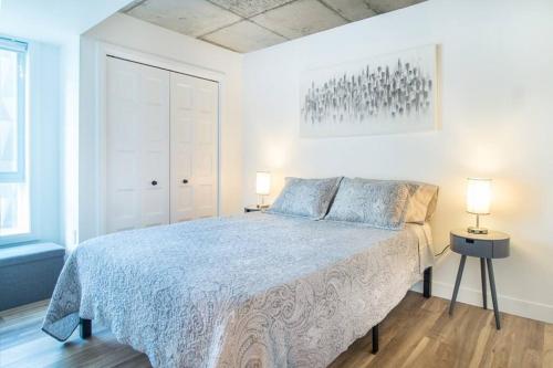 ein weißes Schlafzimmer mit einem Bett und zwei Lampen in der Unterkunft Condo chic, centre-ville piscine, terrasse, gym in Québec