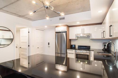 a kitchen with white cabinets and a stainless steel refrigerator at Condo moderne, centre-ville piscine, terrasse, gym in Quebec City
