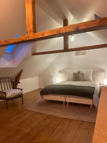a bedroom with a bed and a chair at Le pré de la mer in Urville-Nacqueville